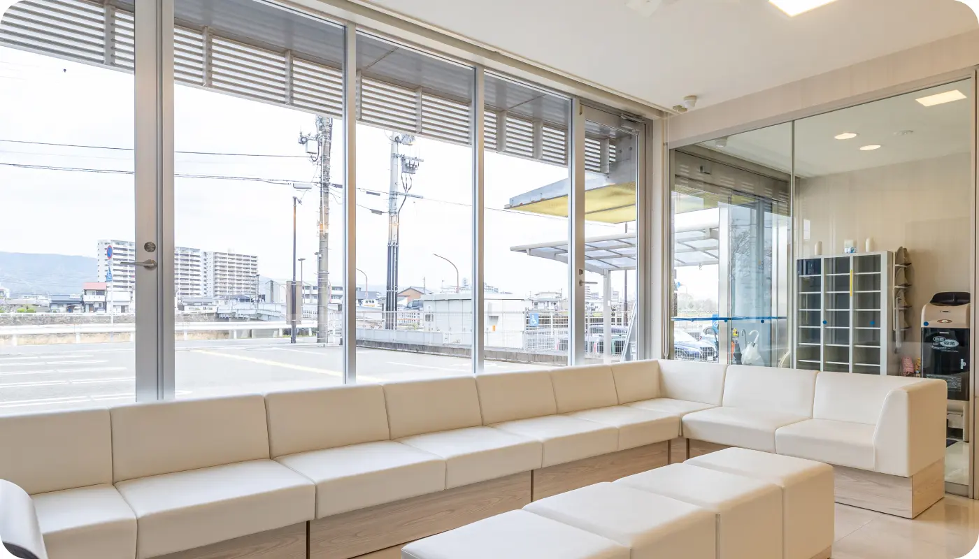 田岡歯科・矯正歯科クリニックの広々とした明るい待合室。白いソファが並ぶ清潔感のある空間。