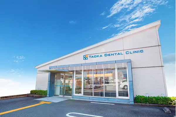 大きな窓とモダンな外装が特徴的な田岡歯科矯正歯科の建物外観と広々とした駐車場