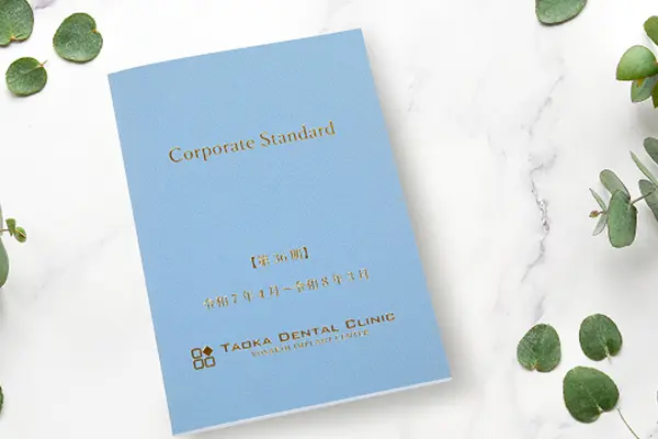 水色の表紙に金文字でCorporate Standardと記された田岡歯科矯正歯科のクレド冊