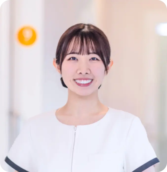 清潔感のある白いユニフォームを着用した女性スタッフの笑顔。歯科医院の採用・求人向けポートレート。